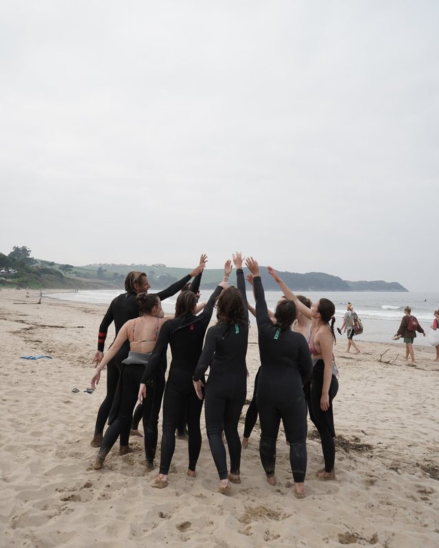 a surf group cheering on the beach after a lesson