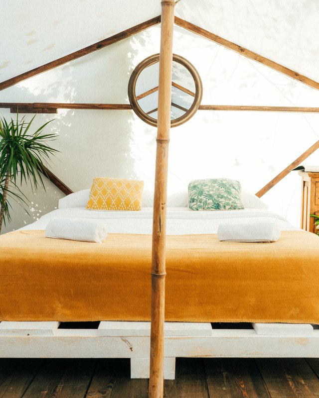 inside a glamping tent at amigos spain, a made double bed